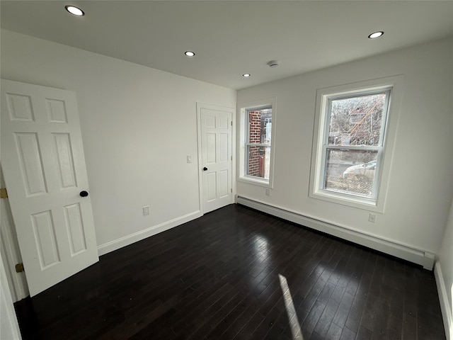 spare room with dark wood-type flooring and a baseboard radiator