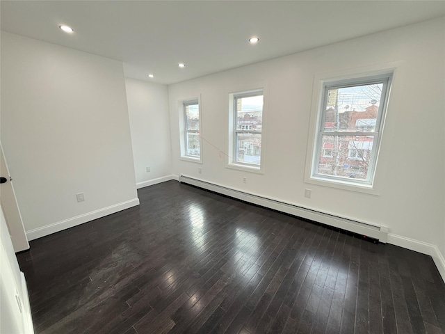 unfurnished room featuring dark hardwood / wood-style floors and a baseboard heating unit