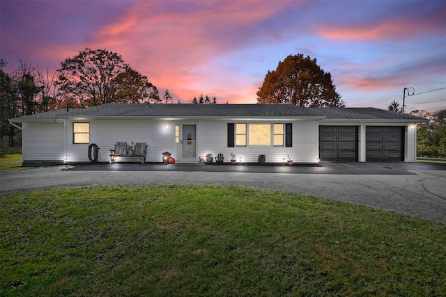 ranch-style house with a garage and a lawn