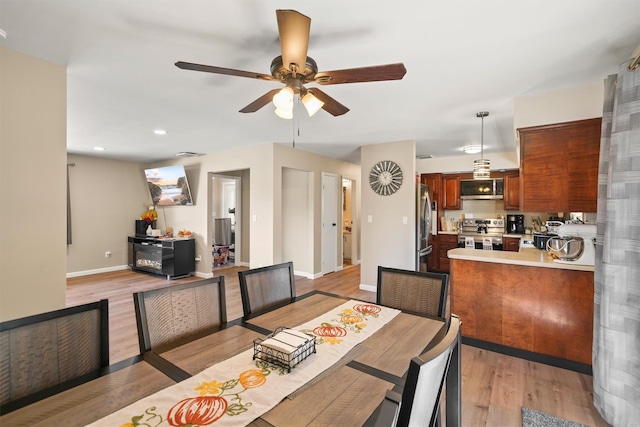 dining space with ceiling fan and light hardwood / wood-style flooring