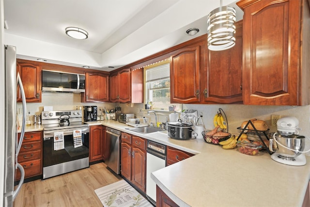 kitchen featuring pendant lighting, sink, appliances with stainless steel finishes, and light hardwood / wood-style flooring