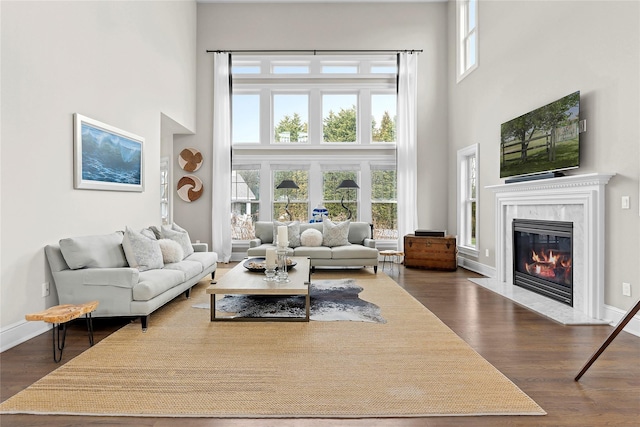 living room featuring dark hardwood / wood-style floors, a towering ceiling, and a fireplace