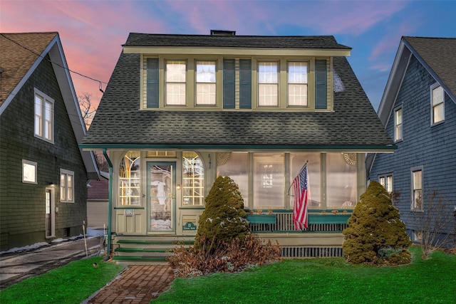 view of front of property with a shingled roof and a front yard