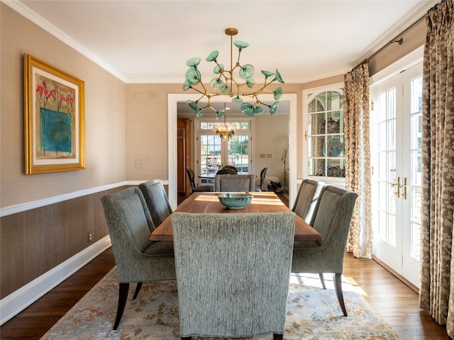 dining space with hardwood / wood-style flooring, ornamental molding, french doors, and an inviting chandelier