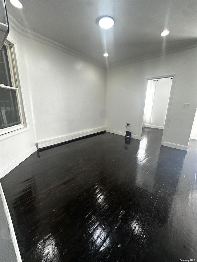 empty room featuring baseboard heating and crown molding