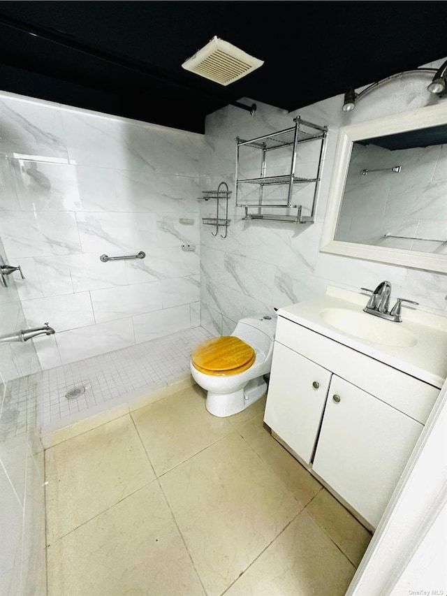 bathroom with tile patterned floors, vanity, toilet, and a tile shower