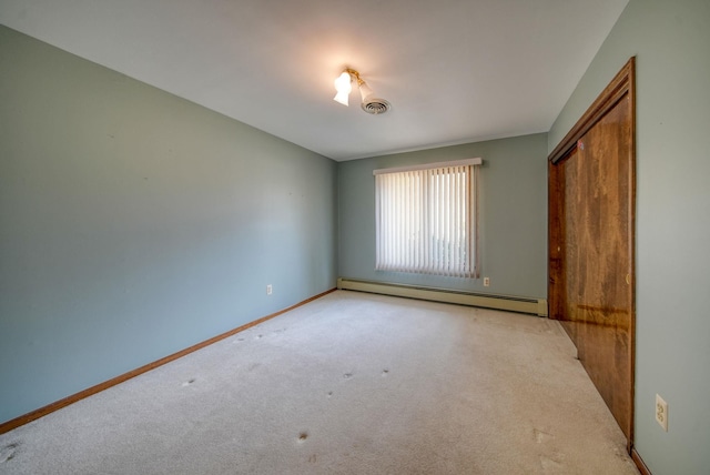 unfurnished room with a baseboard heating unit and light colored carpet