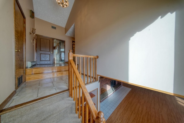 stairs featuring a textured ceiling and lofted ceiling