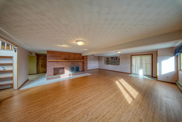 unfurnished living room featuring a brick fireplace, a textured ceiling, and light hardwood / wood-style floors