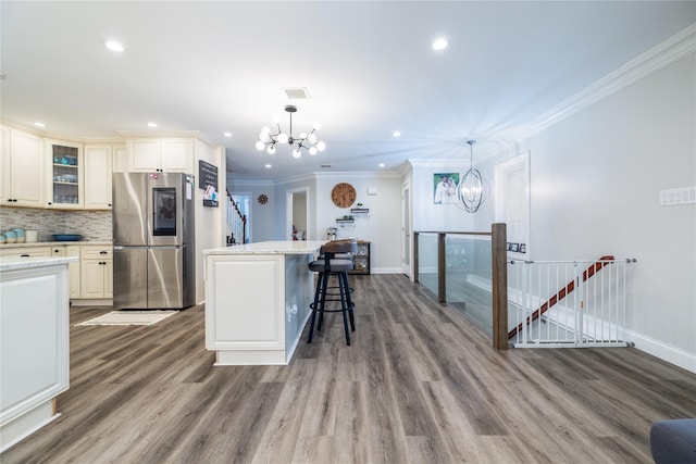 kitchen with pendant lighting, stainless steel fridge, a kitchen island, and an inviting chandelier