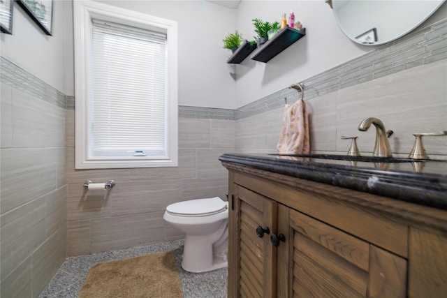 bathroom featuring toilet, tile patterned flooring, vanity, and tile walls