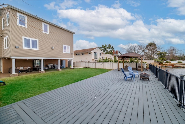 wooden terrace with a water view, a gazebo, a lawn, and an outdoor living space with a fire pit