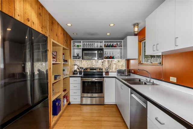 kitchen with white cabinetry, sink, stainless steel appliances, backsplash, and light hardwood / wood-style floors