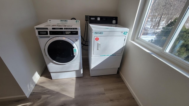 washroom featuring wood finished floors, washing machine and dryer, and baseboards