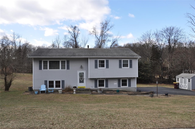 split foyer home with a front lawn and a storage unit