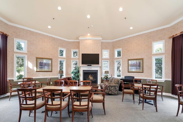 dining room featuring a towering ceiling, a fireplace, crown molding, and light colored carpet