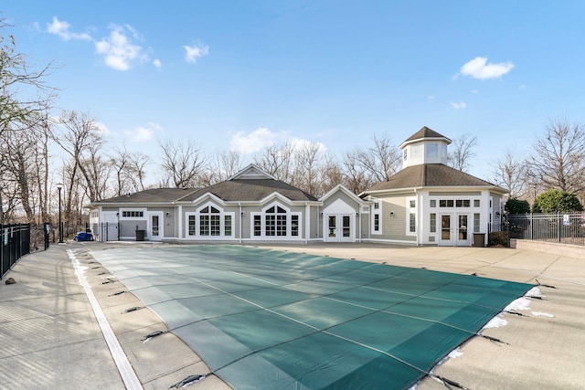 rear view of house featuring a covered pool, french doors, and a patio area