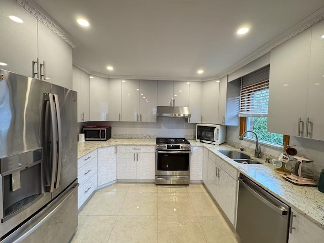 kitchen with sink, light stone counters, appliances with stainless steel finishes, white cabinets, and ornamental molding