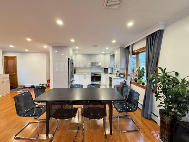 dining area featuring sink, crown molding, baseboard heating, and light hardwood / wood-style flooring