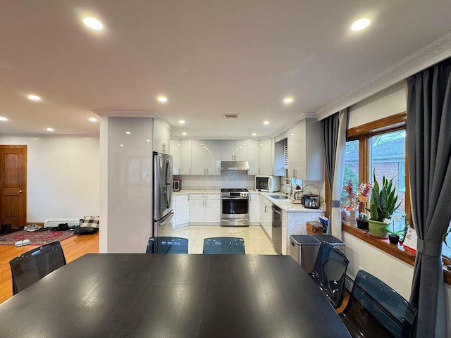 dining space with crown molding, sink, and light wood-type flooring