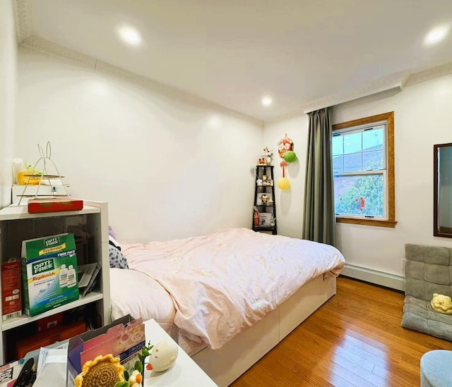 bedroom featuring light hardwood / wood-style flooring and a baseboard heating unit