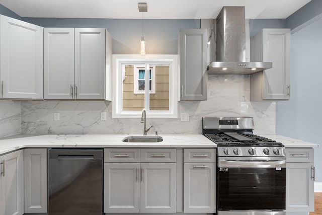 kitchen featuring gray cabinetry, sink, stainless steel appliances, wall chimney range hood, and light stone counters