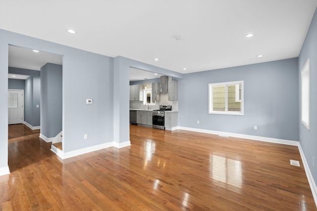 unfurnished living room featuring sink and hardwood / wood-style flooring