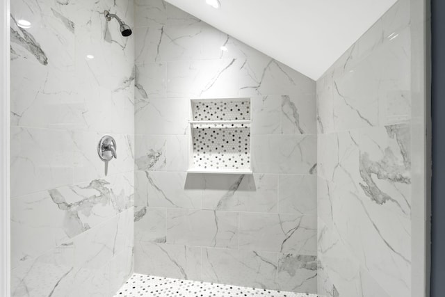 bathroom with a tile shower and vaulted ceiling