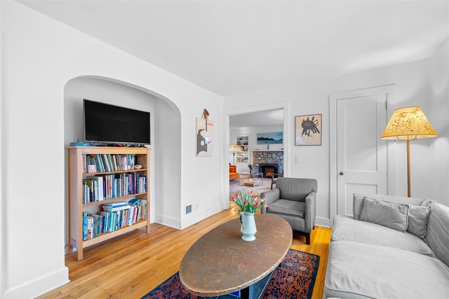 living room featuring a stone fireplace and wood-type flooring