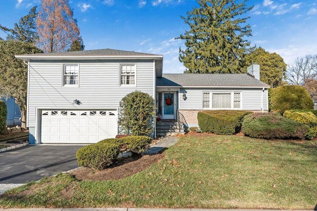 tri-level home featuring a garage and a front lawn