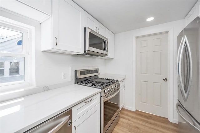 kitchen with white cabinets, appliances with stainless steel finishes, and light hardwood / wood-style flooring