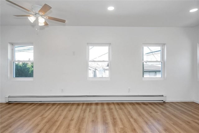 empty room featuring light hardwood / wood-style floors, ceiling fan, and a baseboard heating unit