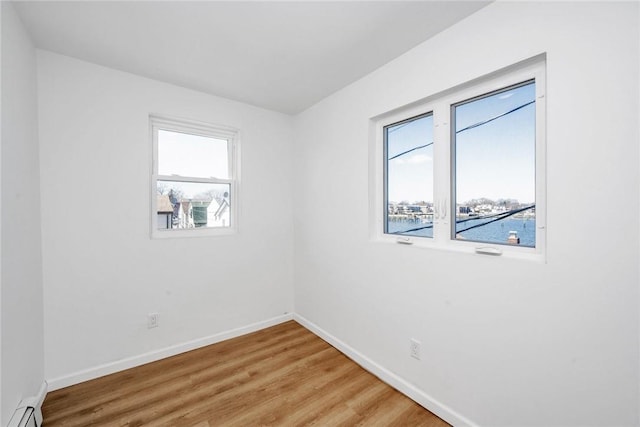 spare room with hardwood / wood-style flooring, a water view, and a baseboard heating unit