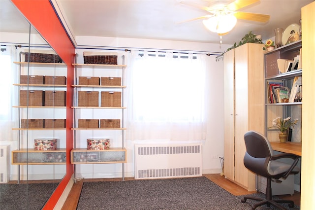 unfurnished office featuring radiator, a healthy amount of sunlight, and ceiling fan