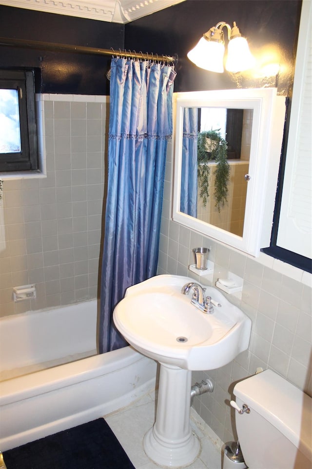 bathroom with plenty of natural light, toilet, shower / bathtub combination with curtain, and tile walls