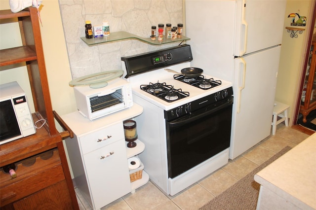 kitchen featuring white gas stove, white cabinets, and light tile patterned flooring