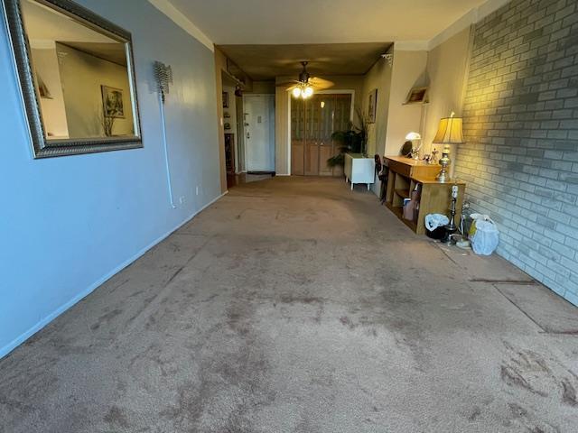 87-10204 204 Steet Unit A-62, Hollis, NY 11423 - unfurnished living room with carpet, brick wall, a ceiling fan, and crown molding