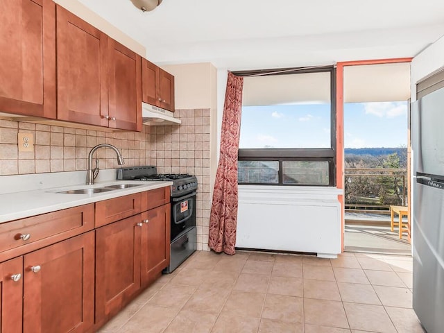 kitchen with sink, stainless steel fridge, black gas stove, decorative backsplash, and light tile patterned floors