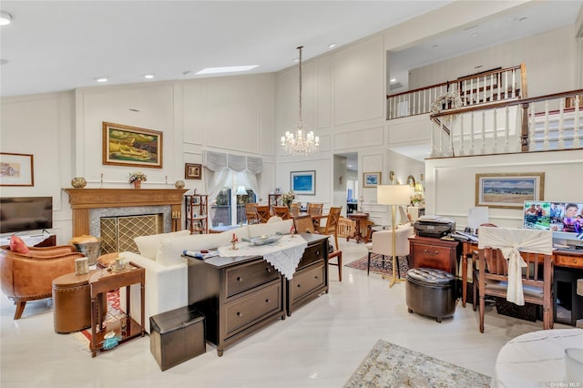 living room featuring a premium fireplace, a high ceiling, and a chandelier