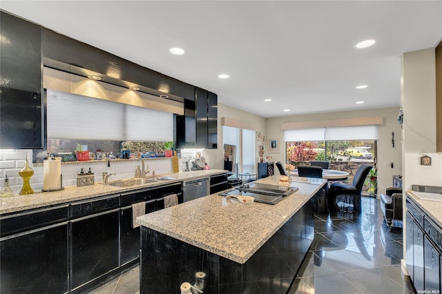 kitchen featuring light stone countertops, a center island, sink, decorative backsplash, and appliances with stainless steel finishes