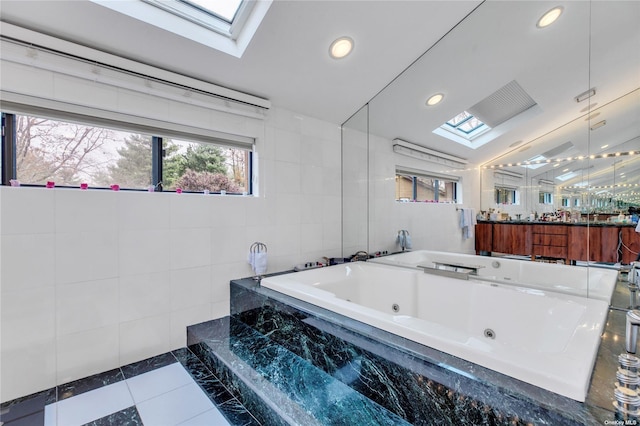 bathroom with vanity, tile patterned floors, a skylight, tile walls, and tiled tub