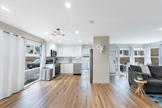 kitchen with light hardwood / wood-style flooring, white cabinets, plenty of natural light, and appliances with stainless steel finishes