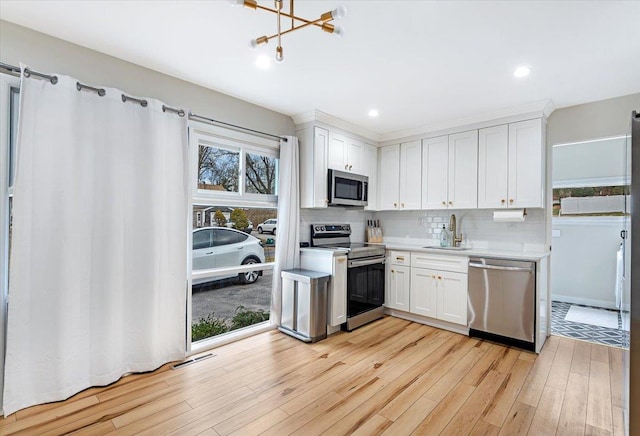 kitchen with appliances with stainless steel finishes, white cabinetry, plenty of natural light, and sink