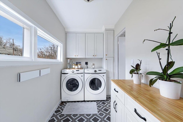 clothes washing area with separate washer and dryer and cabinets