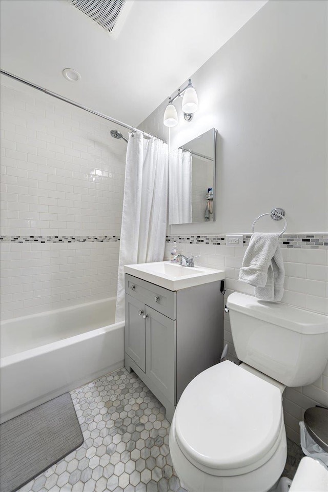 full bathroom with vanity, shower / bath combo, tile patterned flooring, toilet, and tile walls