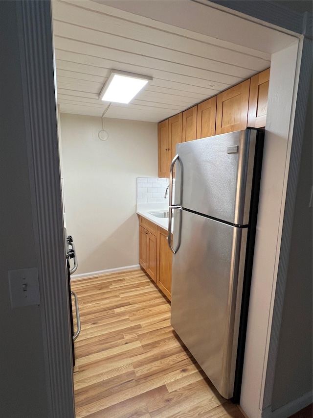 kitchen featuring stainless steel refrigerator, light hardwood / wood-style floors, decorative backsplash, and stove