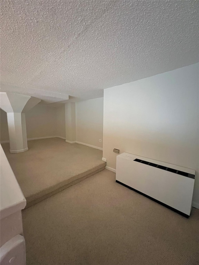 interior space with carpet floors, a textured ceiling, and baseboard heating