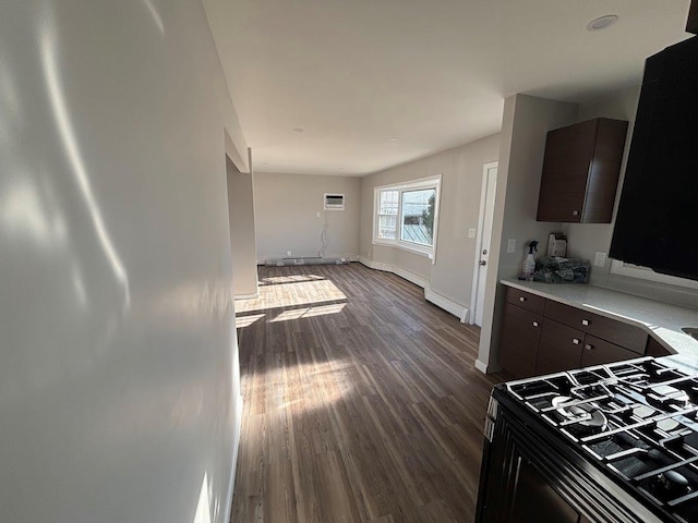 kitchen featuring dark hardwood / wood-style floors, a wall mounted AC, dark brown cabinetry, and range with gas cooktop