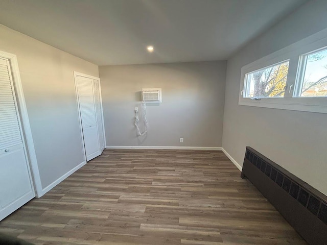 interior space featuring radiator, a wall mounted air conditioner, and dark hardwood / wood-style flooring