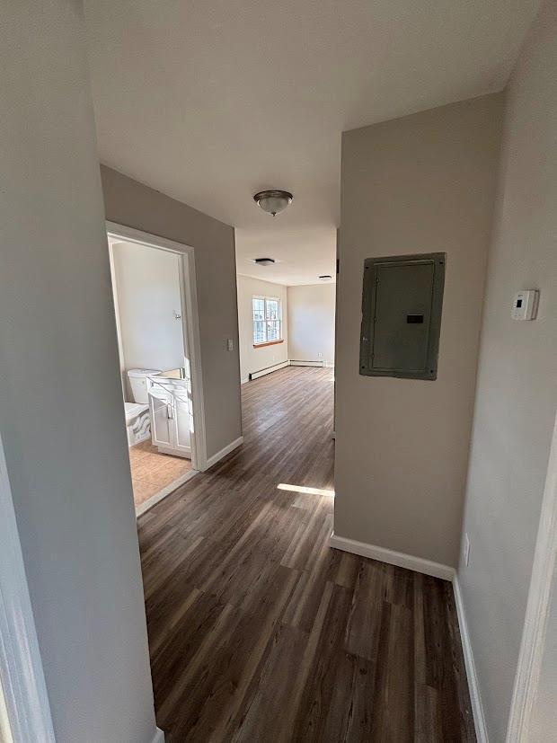 hallway with dark wood-type flooring and electric panel